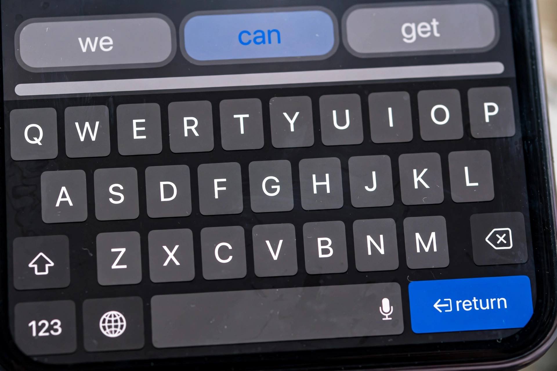 Close-up of iPhone keyboard with predictive text suggestions visible
