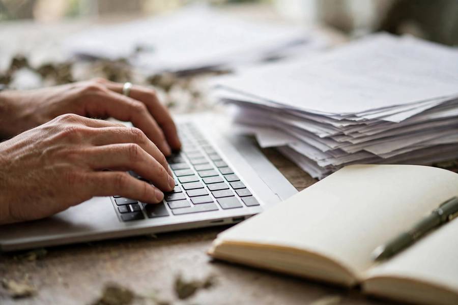 Hands typing a research paper introduction on a laptop keyboard