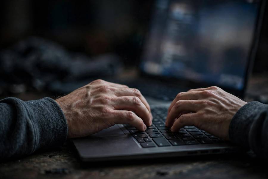 Anonymous typing on a laptop with blurred screen