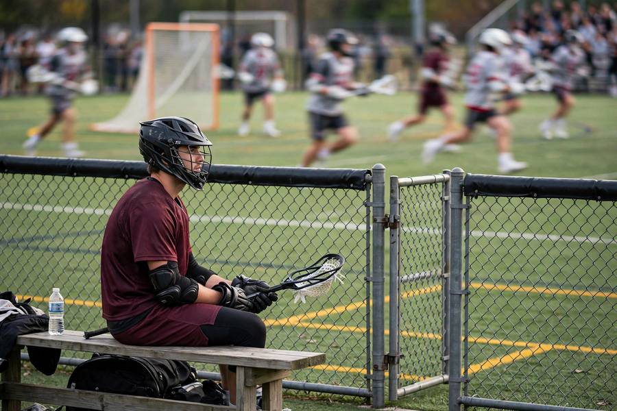 Lacrosse player serving penalty time in the penalty box area beside the field