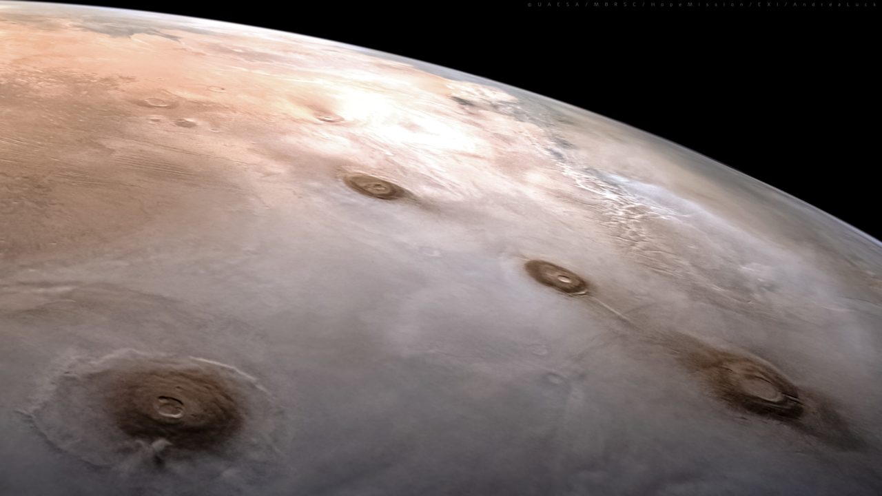 Mars from orbit showing the line of the Tharsis volcanoes, with Olympus Mons near the horizon