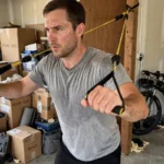 Benefits of Resistance Band Training: Why They Work Man performing a resistance band chest press in a home garage gym, showing the benefits of resistance band training at home