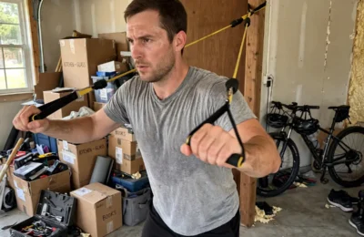 Man performing a resistance band chest press in a home garage gym, showing the benefits of resistance band training at home