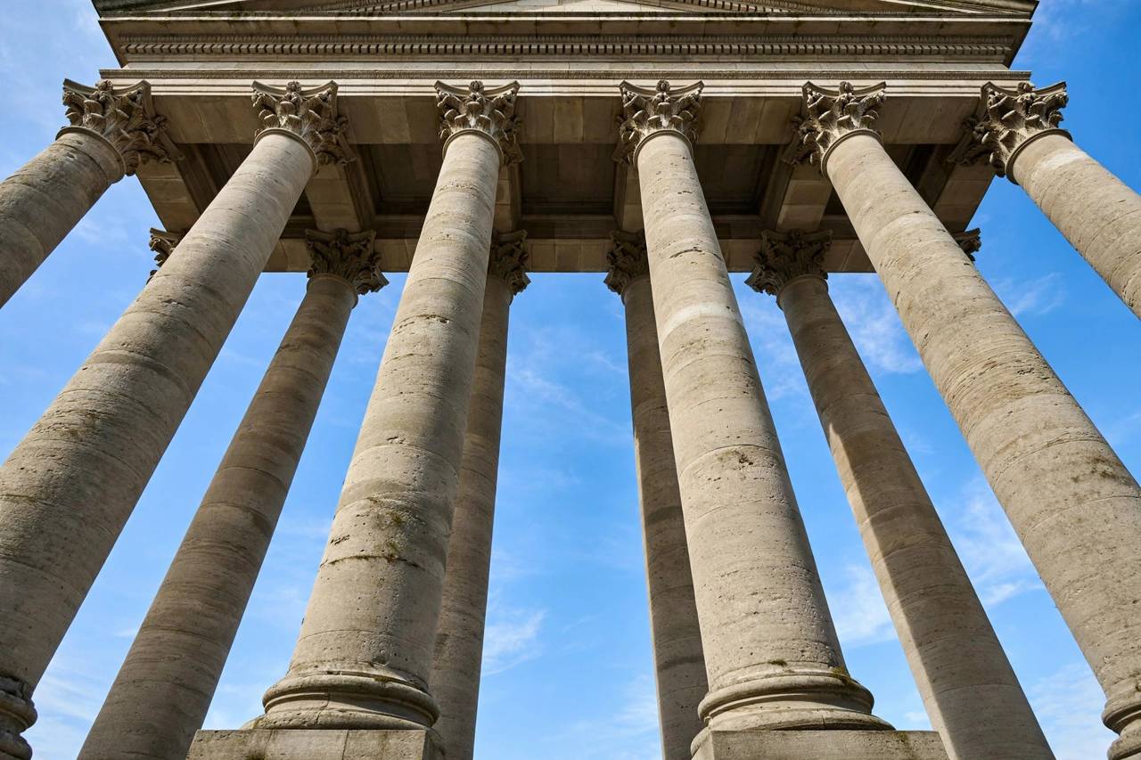 Classical courthouse columns viewed from below against sky
