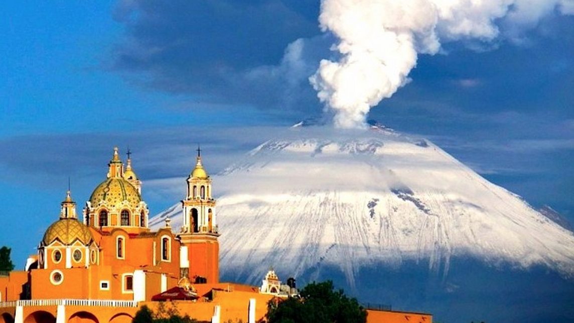 Popocatepetl volcano smoking behind the church at Cholula, Mexico, a town in its shadow