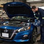 Nissan CVT Transmission Problems: Models Affected and What to Watch For Nissan sedan in a repair shop with the hood open for transmission inspection