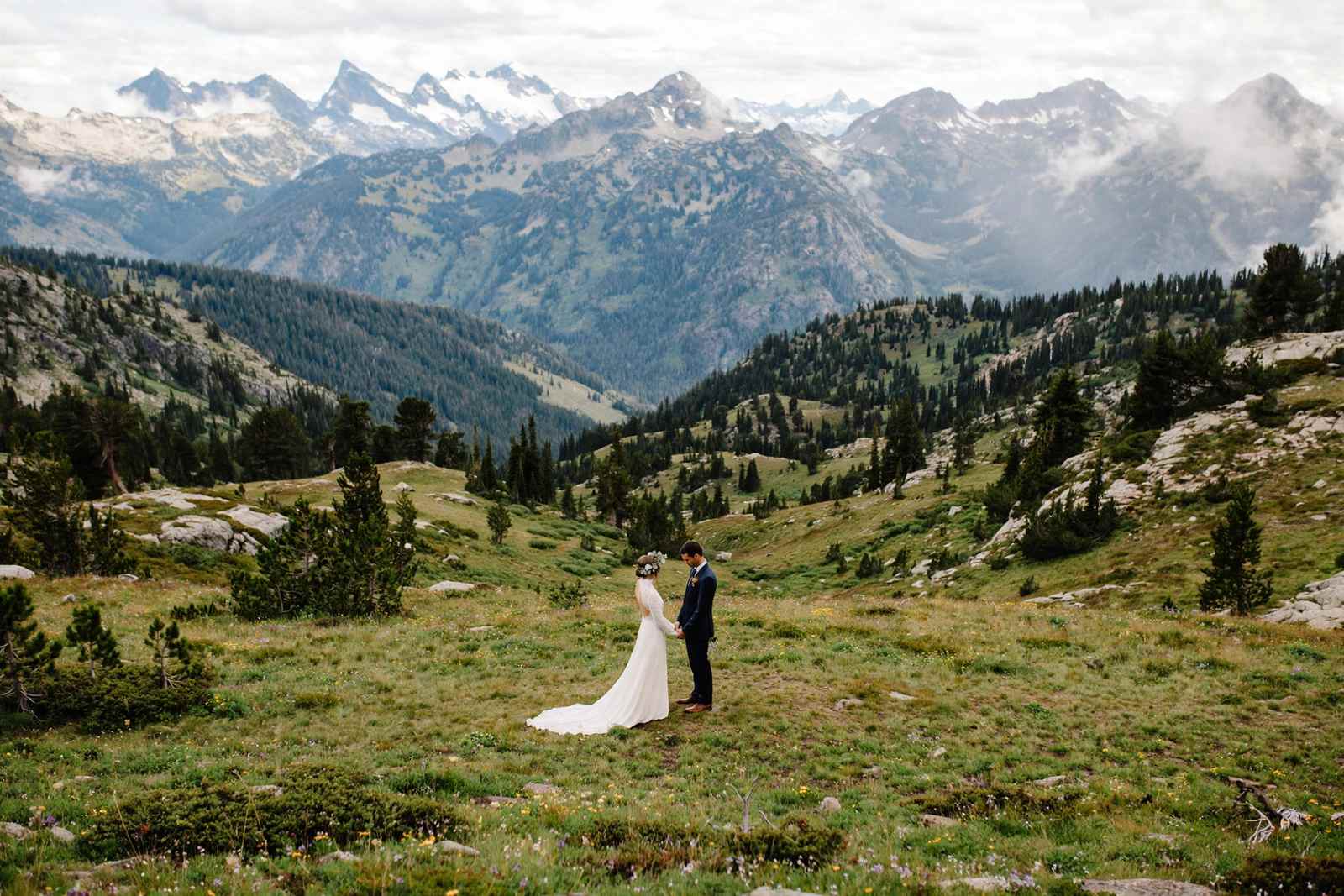 Couple exchanging vows outdoors with mountains in the background
