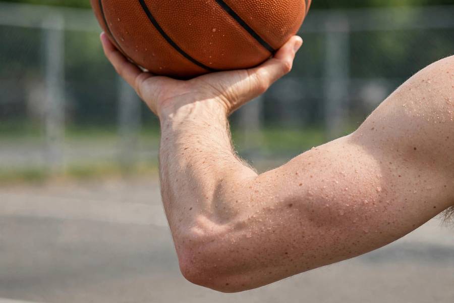 Photorealistic close-up of shooting elbow aligned under the ball at the set point