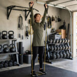 8 Best Shoulder Exercises With Resistance Bands (Full Workout) Woman performing resistance band overhead press while standing on the band