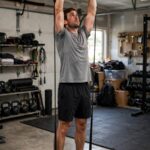 8 Best Shoulder Exercises With Resistance Bands (Full Workout) Man performing resistance band overhead press while standing on the band