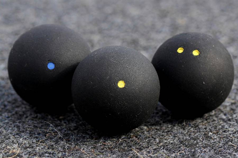 Photorealistic close-up of squash balls showing blue dot, single yellow dot and double yellow dot varieties