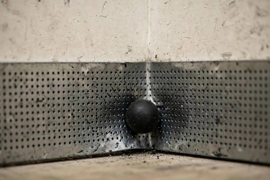 Photorealistic close-up of a squash ball hitting the tin on the front wall, rally-ending moment