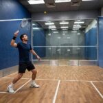 Squash Serve Rules: Boxes, Heights, Foot Faults and Common Mistakes Photorealistic photo of a squash player serving from inside the service box, proper stance, indoor court