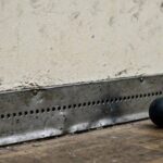 The Squash Tin Rule Explained: What 'Down' Means and Why It Exists Photorealistic close-up of the metal tin strip along the bottom of a squash front wall, ball nearby