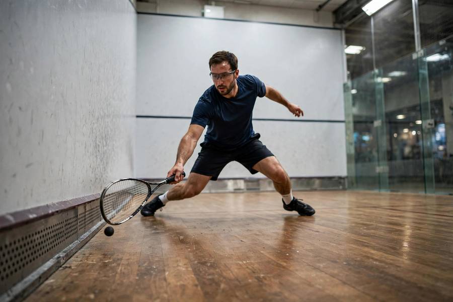 Photorealistic action shot of a squash player hitting a low drop shot just above the tin, front corner