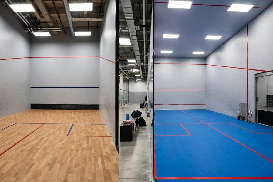 Photorealistic side-by-side comparison photo of a squash court and a racquetball court, bright indoor sports facility