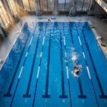 Swimming Workouts for Beginners: The Pool Plans I Wish I'd Started With Beginner swimmer practicing freestyle in a lane during swimming workouts for beginners