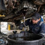 Transmission Fluid Change vs Flush: Which One Does Your Car Actually Need? Mechanic draining old transmission fluid during a drain and fill service