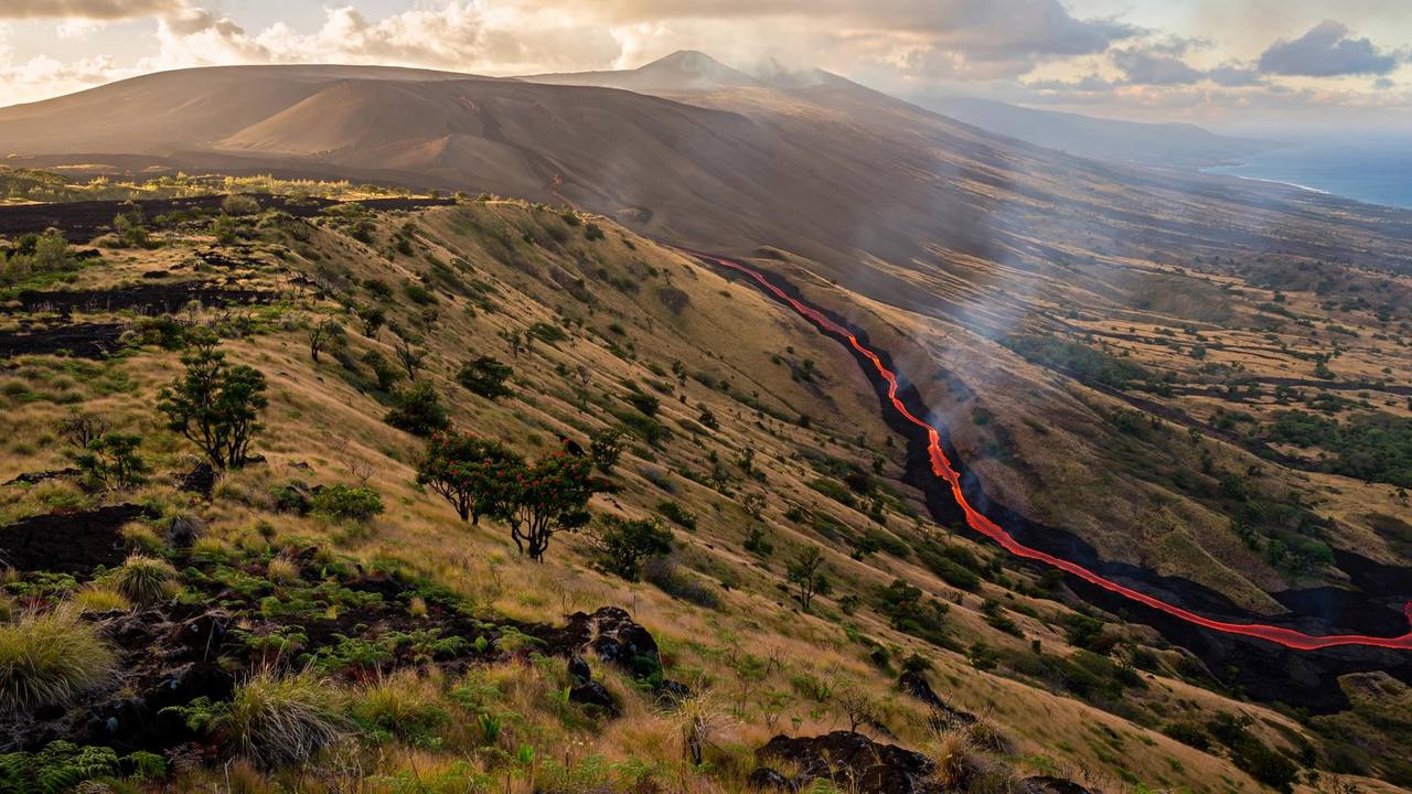 Wide shield volcano with gentle slopes and a thin stream of lava