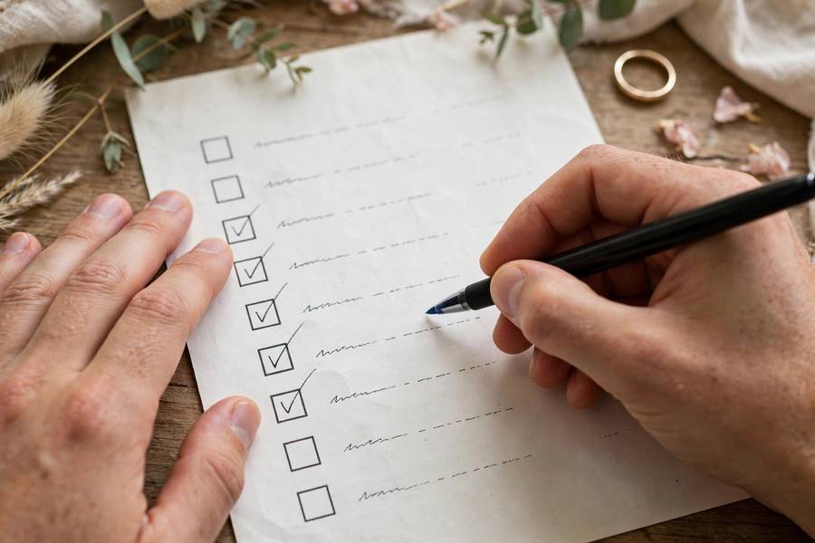 Hands checking off wedding tasks