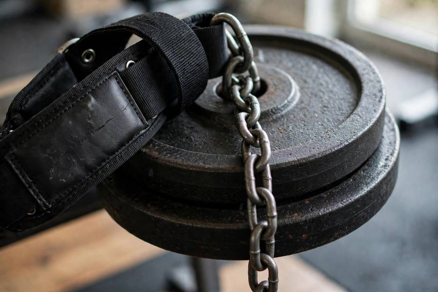 Close-up of dip belt chain threaded through weight plates before a pull-up set
