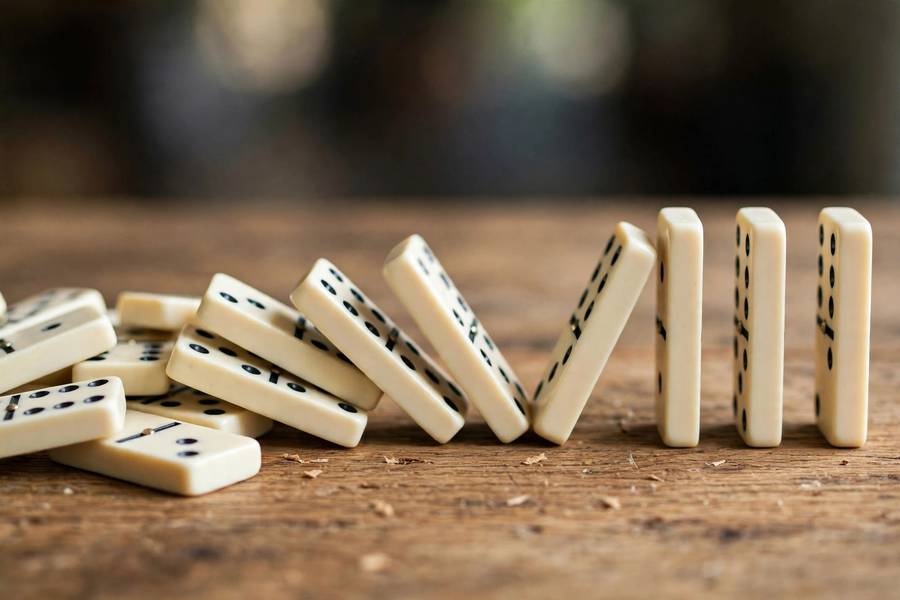 Falling dominoes representing the chain reaction of what causes AI bias