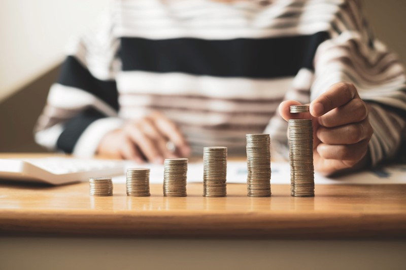 Stacks of coins growing taller on a table, symbolizing savings growth