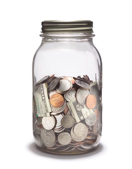 Glass savings jar filled with cash and coins