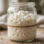 What Is Sourdough Starter? Your Friendly Guide to Baking's Living Ingredient Bubbly sourdough starter rising in a glass jar with a rubber band marking its level