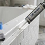 What Is the Best Caulk for Bathrooms? Pro Guide Caulk gun applying white silicone sealant along a bathtub edge in a bathroom