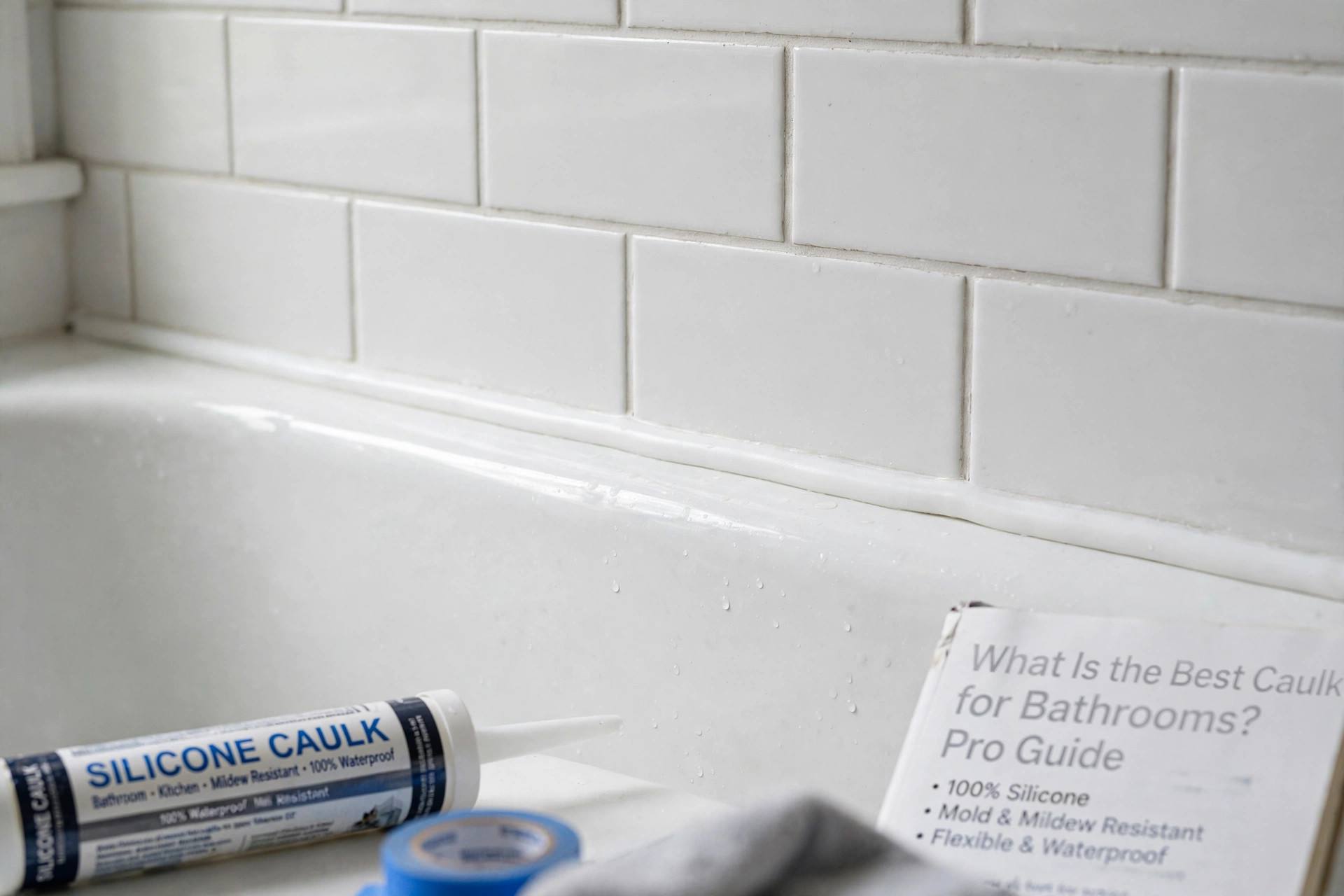 Close-up of a smooth clean caulk line between white tile and bathtub