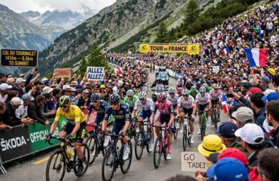 Tour de France peloton climbing a mountain pass before cheering crowds